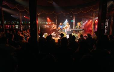 A group of performers singing and playing instruments on stage.